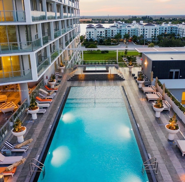 pool at dusk featuring a water view