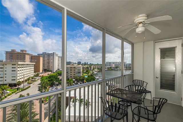 sunroom / solarium featuring ceiling fan and a water view