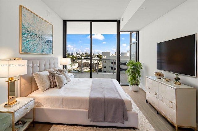 bedroom featuring access to outside, light hardwood / wood-style flooring, and floor to ceiling windows