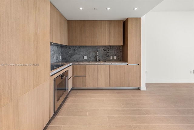 kitchen with sink, black electric stovetop, wall oven, tasteful backsplash, and light brown cabinetry