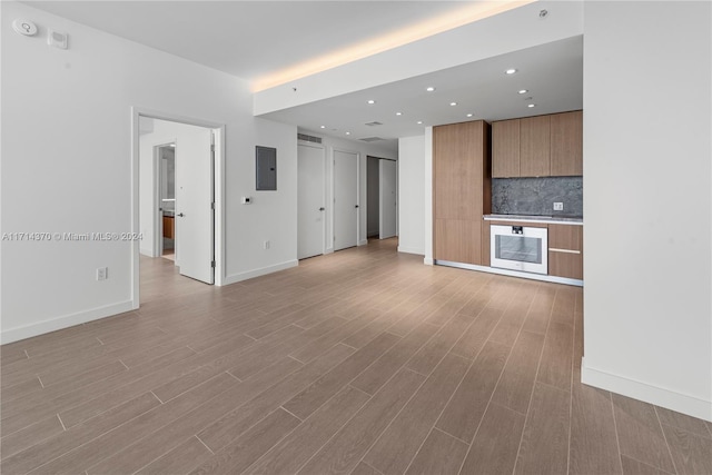 unfurnished living room featuring electric panel and light hardwood / wood-style flooring