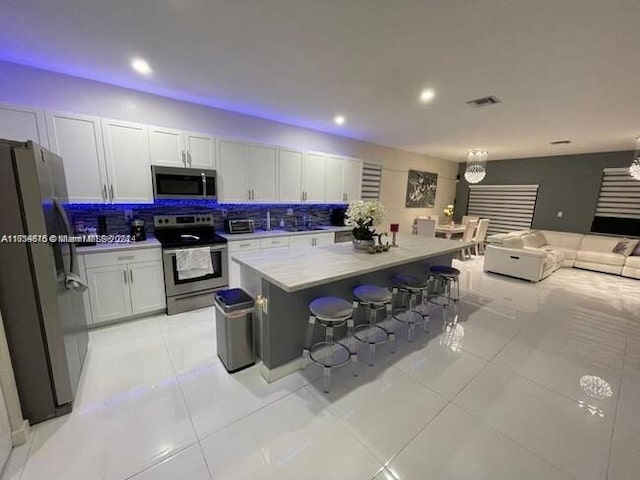 kitchen featuring a kitchen breakfast bar, light tile patterned floors, tasteful backsplash, a kitchen island, and stainless steel appliances