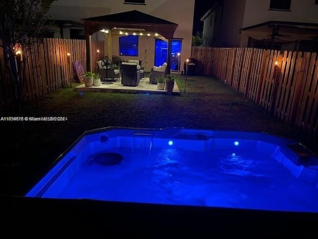 pool at night with a gazebo and a patio