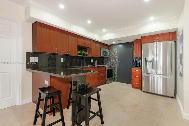 kitchen with a kitchen breakfast bar, decorative backsplash, dark stone countertops, kitchen peninsula, and stainless steel appliances