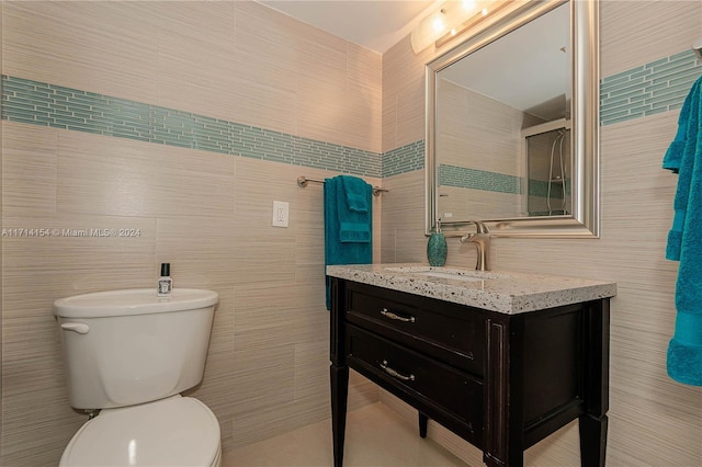 bathroom featuring vanity, toilet, and tile walls