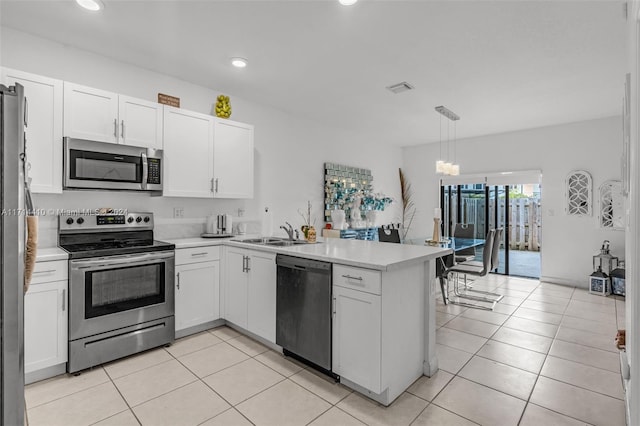 kitchen with sink, kitchen peninsula, pendant lighting, white cabinets, and appliances with stainless steel finishes