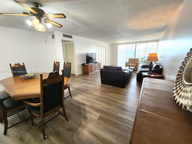 dining space with dark wood-type flooring, expansive windows, visible vents, and a textured ceiling