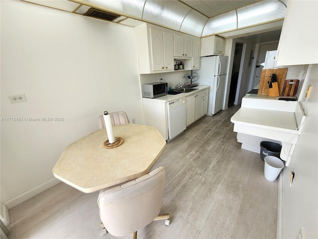 kitchen featuring white appliances, visible vents, baseboards, white cabinetry, and light wood-type flooring