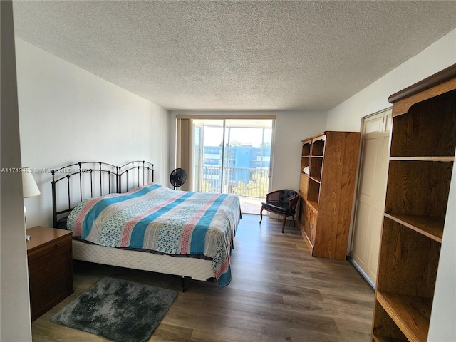 bedroom with a textured ceiling, access to outside, and dark wood-style flooring