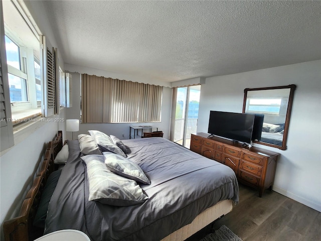 bedroom with dark wood-style flooring, a textured ceiling, and baseboards