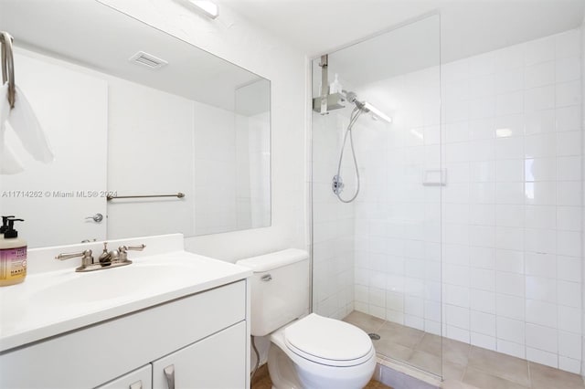 bathroom with tiled shower, vanity, and toilet