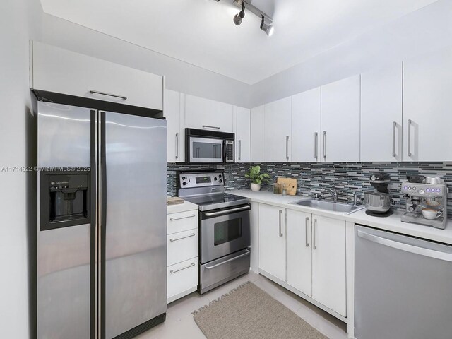 1018 Meridian Ave Unit 4, Miami Beach, FL 33139 - kitchen with appliances with stainless steel finishes, a sink, light countertops, decorative backsplash, and white cabinets