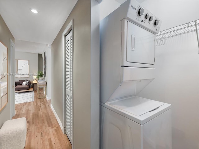 laundry area featuring stacked washer and dryer and light wood-type flooring