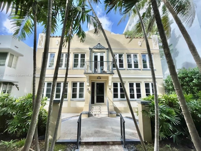 view of front facade with a patio area, french doors, and a balcony