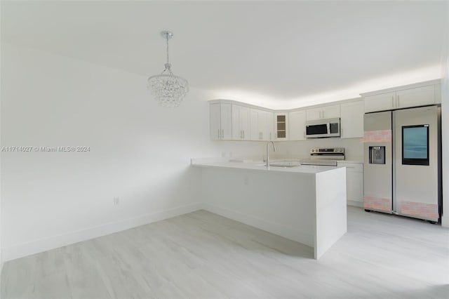 kitchen with kitchen peninsula, stainless steel appliances, sink, white cabinets, and hanging light fixtures