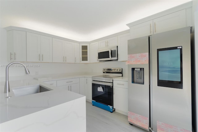 kitchen with light stone counters, sink, white cabinets, and appliances with stainless steel finishes