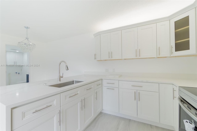 kitchen featuring an inviting chandelier, white cabinets, sink, hanging light fixtures, and kitchen peninsula