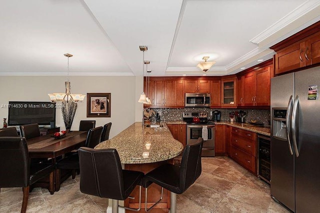 kitchen with hanging light fixtures, ornamental molding, stainless steel appliances, and a breakfast bar area