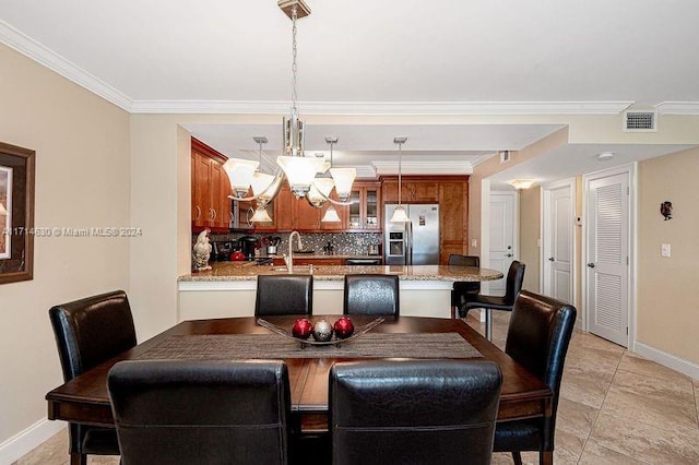 dining area with a chandelier, ornamental molding, and sink