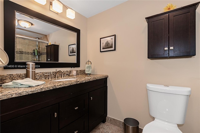 bathroom featuring vanity, a shower with shower door, and toilet