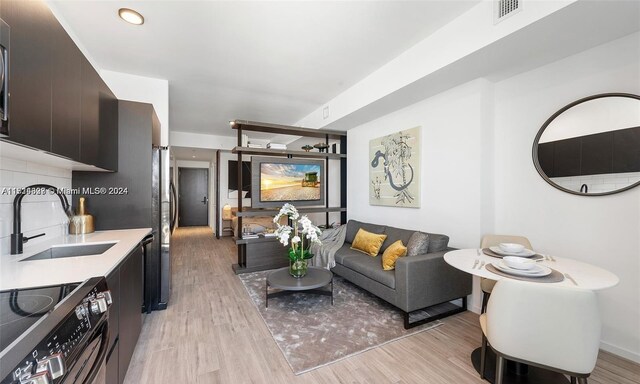 living room featuring sink and light hardwood / wood-style flooring