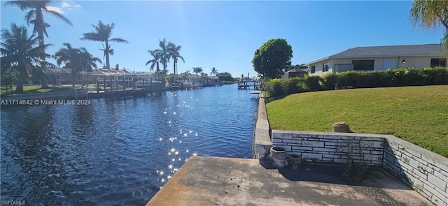 view of dock with a yard and a water view