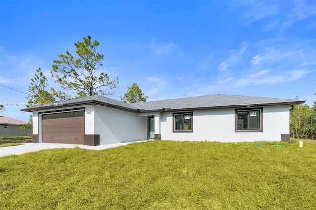 view of front of home with stucco siding, an attached garage, and a front lawn