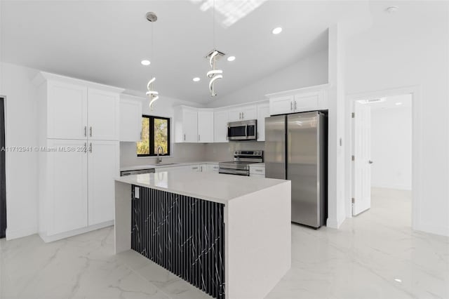 kitchen featuring white cabinets, vaulted ceiling, appliances with stainless steel finishes, decorative light fixtures, and a kitchen island