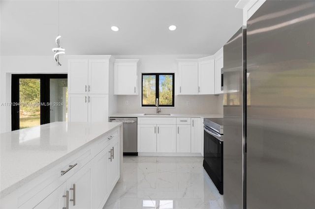 kitchen featuring appliances with stainless steel finishes, recessed lighting, a sink, plenty of natural light, and light marble finish floors