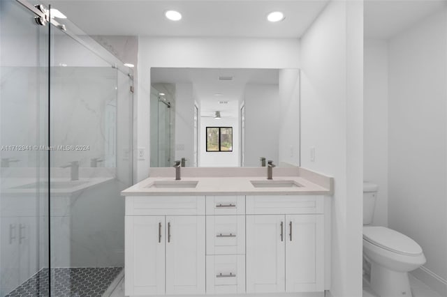 full bath with a marble finish shower, toilet, double vanity, and recessed lighting