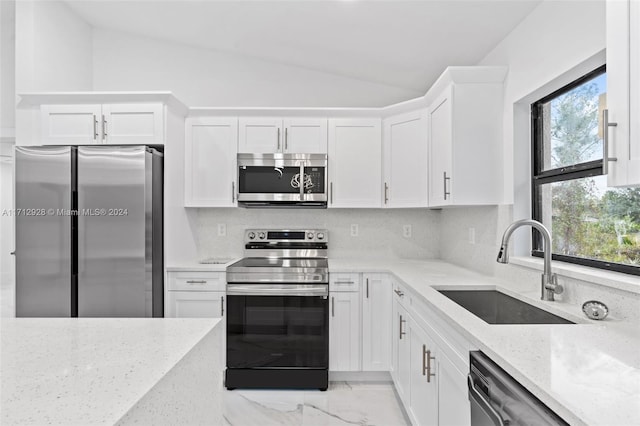 kitchen featuring light stone countertops, sink, white cabinetry, stainless steel appliances, and decorative backsplash