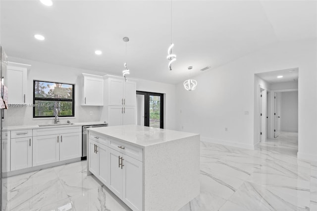 kitchen featuring white cabinetry, sink, a kitchen island, and decorative light fixtures