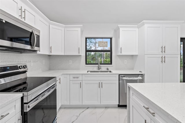 kitchen with light stone countertops, sink, white cabinets, and appliances with stainless steel finishes