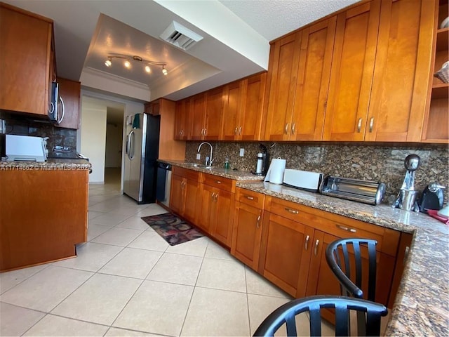 kitchen featuring backsplash, a raised ceiling, light stone countertops, light tile patterned floors, and stainless steel appliances