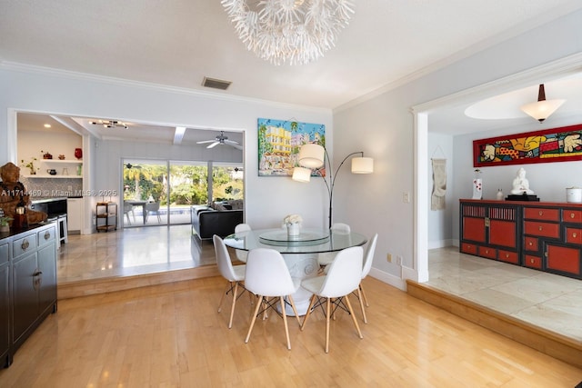 dining space featuring beamed ceiling, ornamental molding, ceiling fan with notable chandelier, and light wood-type flooring