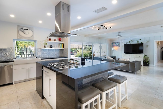 kitchen featuring sink, a breakfast bar area, stainless steel appliances, island range hood, and white cabinets