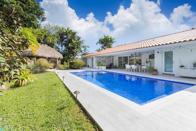 view of pool with ceiling fan, a patio area, and a lawn