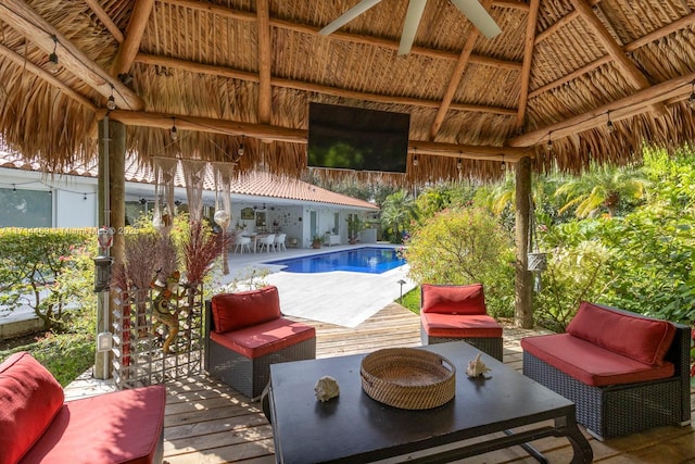 view of pool with an outdoor living space, a wooden deck, a gazebo, and ceiling fan