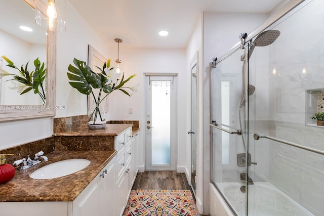 bathroom featuring vanity, hardwood / wood-style floors, and combined bath / shower with glass door