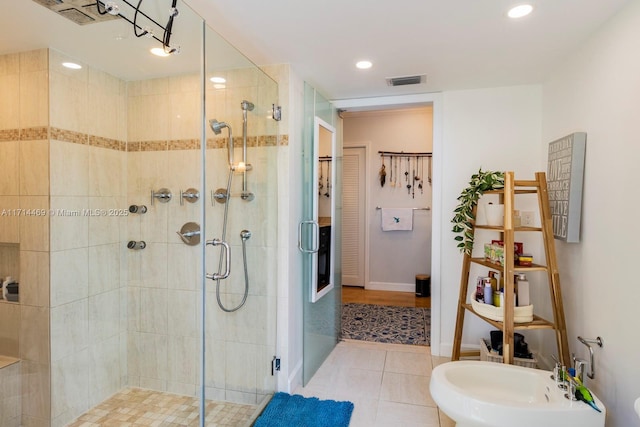 bathroom with an enclosed shower, sink, tile patterned flooring, and a bidet