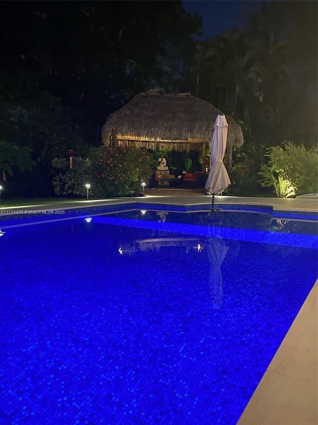 pool at twilight featuring a gazebo