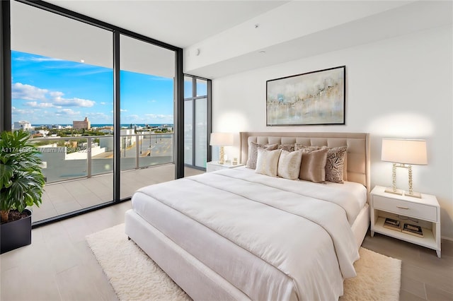 bedroom with access to outside, floor to ceiling windows, and hardwood / wood-style flooring