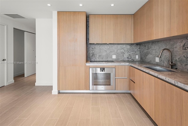 kitchen with stainless steel oven, light brown cabinets, sink, decorative backsplash, and black electric cooktop