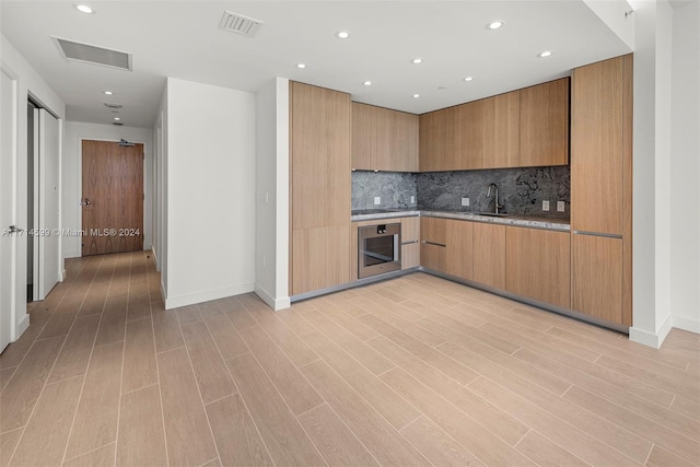 kitchen with decorative backsplash, oven, and sink