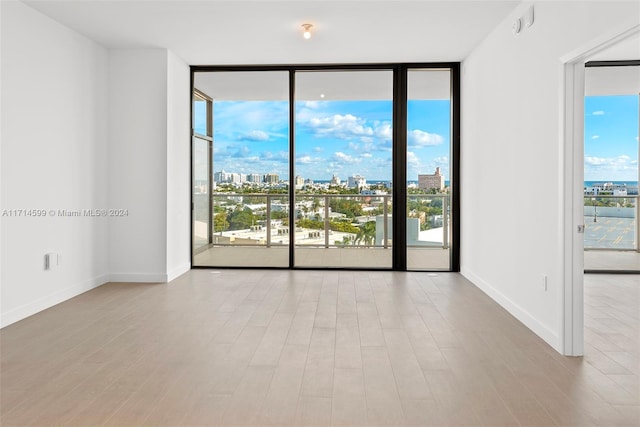 unfurnished room with plenty of natural light, floor to ceiling windows, and light hardwood / wood-style flooring