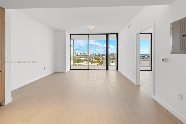 spare room with floor to ceiling windows and light wood-type flooring