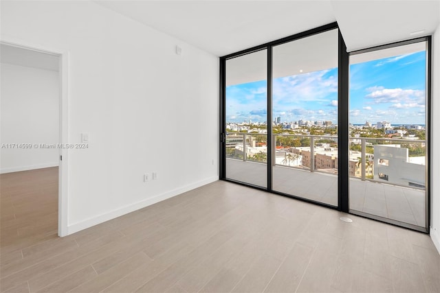 spare room featuring floor to ceiling windows and light hardwood / wood-style flooring