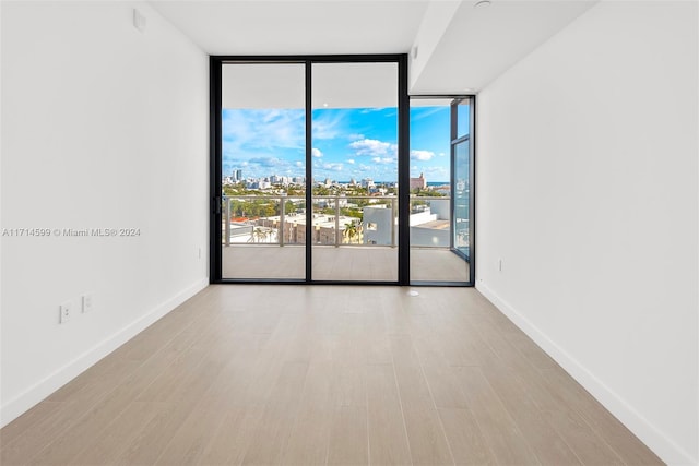 unfurnished room featuring floor to ceiling windows and light wood-type flooring