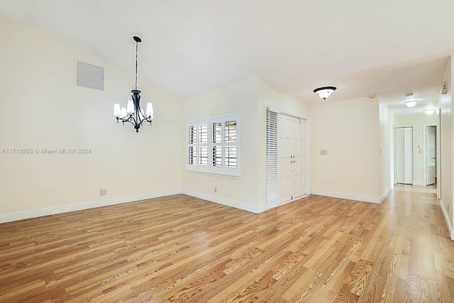 unfurnished room featuring a notable chandelier, light hardwood / wood-style floors, and vaulted ceiling