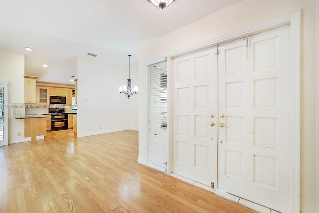 foyer entrance featuring sink, light hardwood / wood-style floors, and a notable chandelier